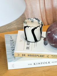 Ella Glass Candle in ivory and black striped hand-painted glass on stacked books with decorative decor