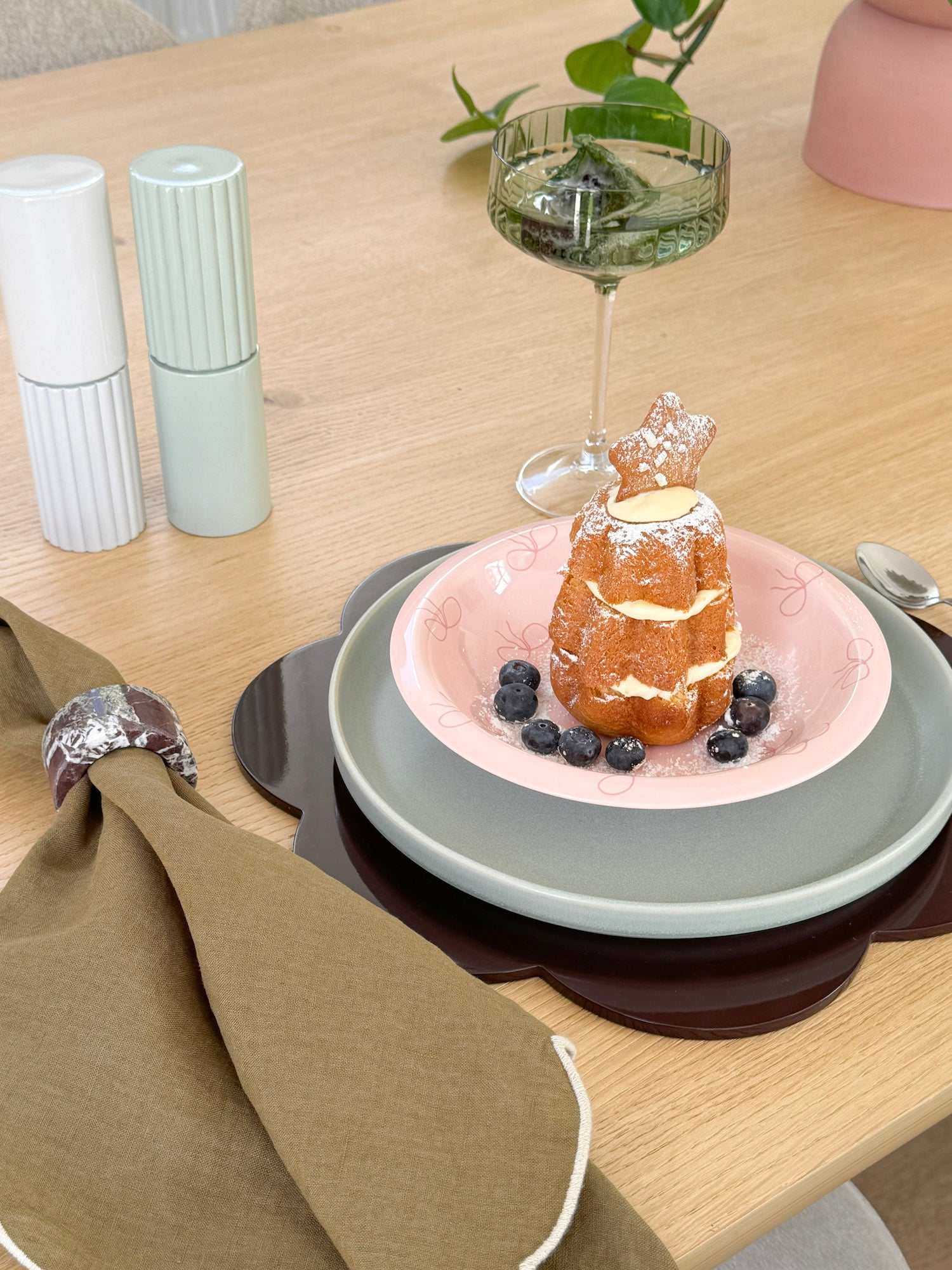 Pink norsu Studio Bow Bowl with deep pink bow design holding dessert on layered plates on wooden table setting