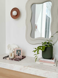 norsu Studio Scalloped Magnetic Photo Frame in blush on marble surface with decor and green plant nearby