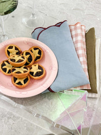 norsu Studio Bow Bowl in pink with deep pink bow holding star-shaped tartlets on a table with folded cloth napkins
