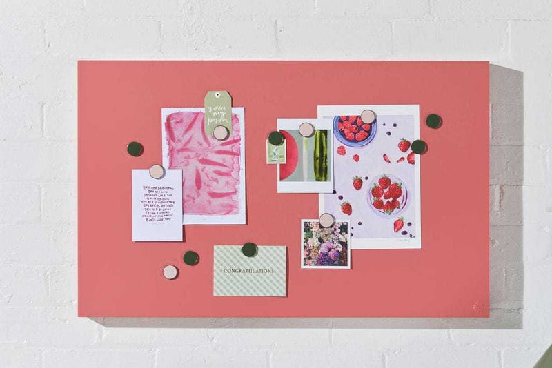 Berry colored magnetic story board with notes and photos attached using round magnets on a white wall