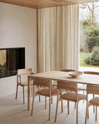 Ethnicraft PI Dining Chair in natural oak wood around a matching wooden dining table in a modern minimalist dining room.