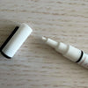 White liquid chalk marker with fine reversible nib and black cap on wooden surface