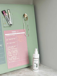 Blush reusable fridge shopping and to-do list with whiteboard markers and cleaning spray on green fridge door
