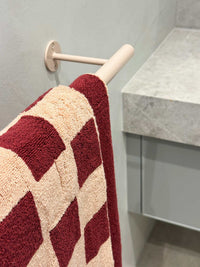 Loop Home Hand Towel in Ruby and Almond Blush pinstripe organic cotton hanging on bathroom rail.