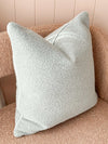 norsu Studio Cushion in powder blue boucle with white leather piping on a textured chair