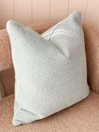 norsu Studio Cushion in powder blue boucle with white leather piping on a textured chair