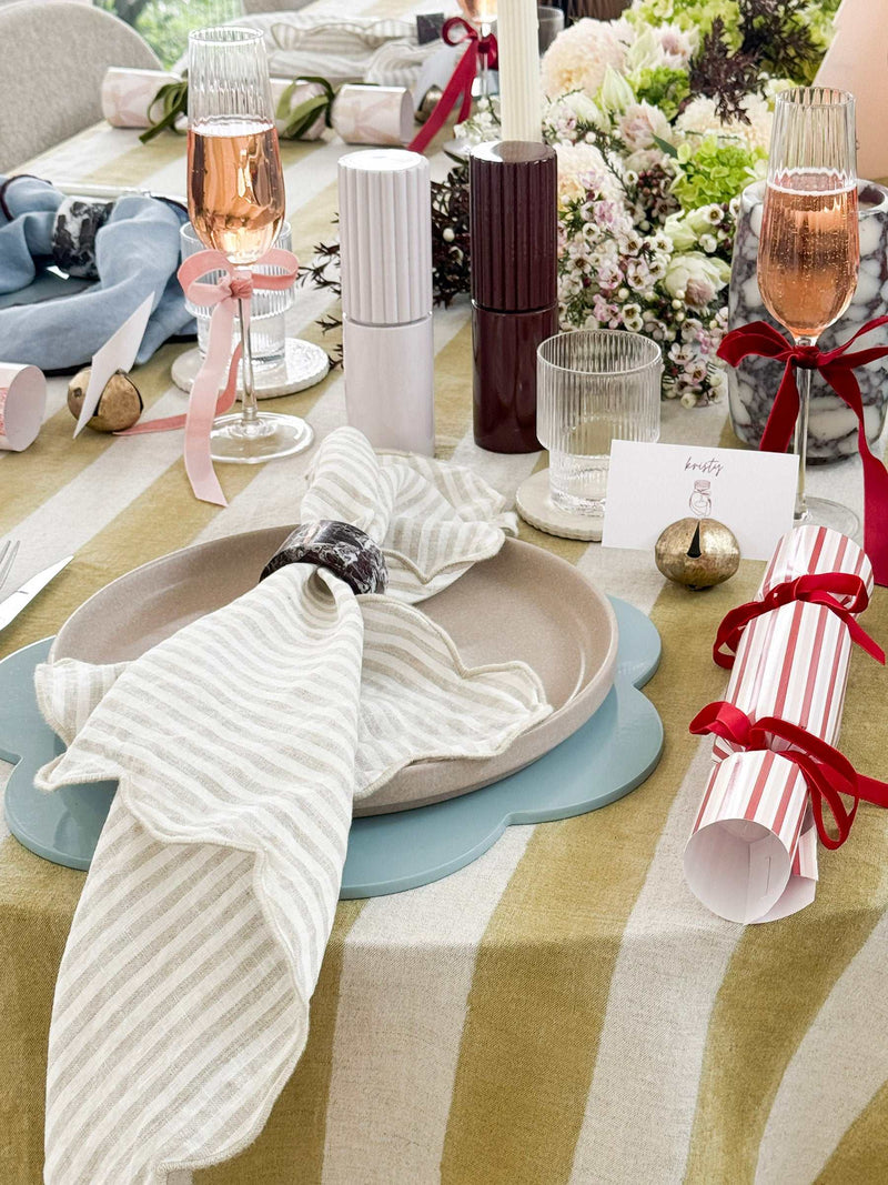 Set of 4 norsu Studio Linen Napkins in oatmeal stripe with scalloped edges on a styled dining table.