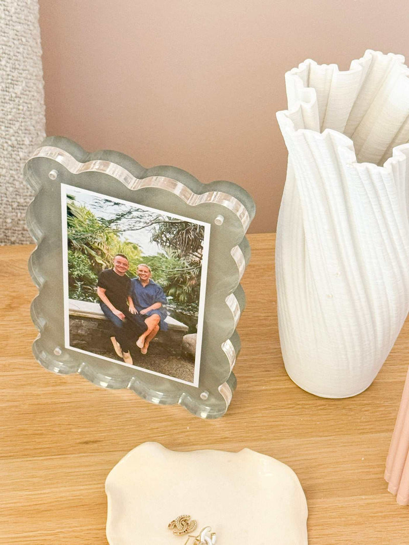 norsu Studio scalloped magnetic photo frame with acrylic finish displaying a portrait photo on a wooden surface next to a white decorative vase