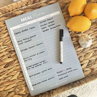 Sky blue magnet meal planner on woven surface with marker and lemons for fridge organization