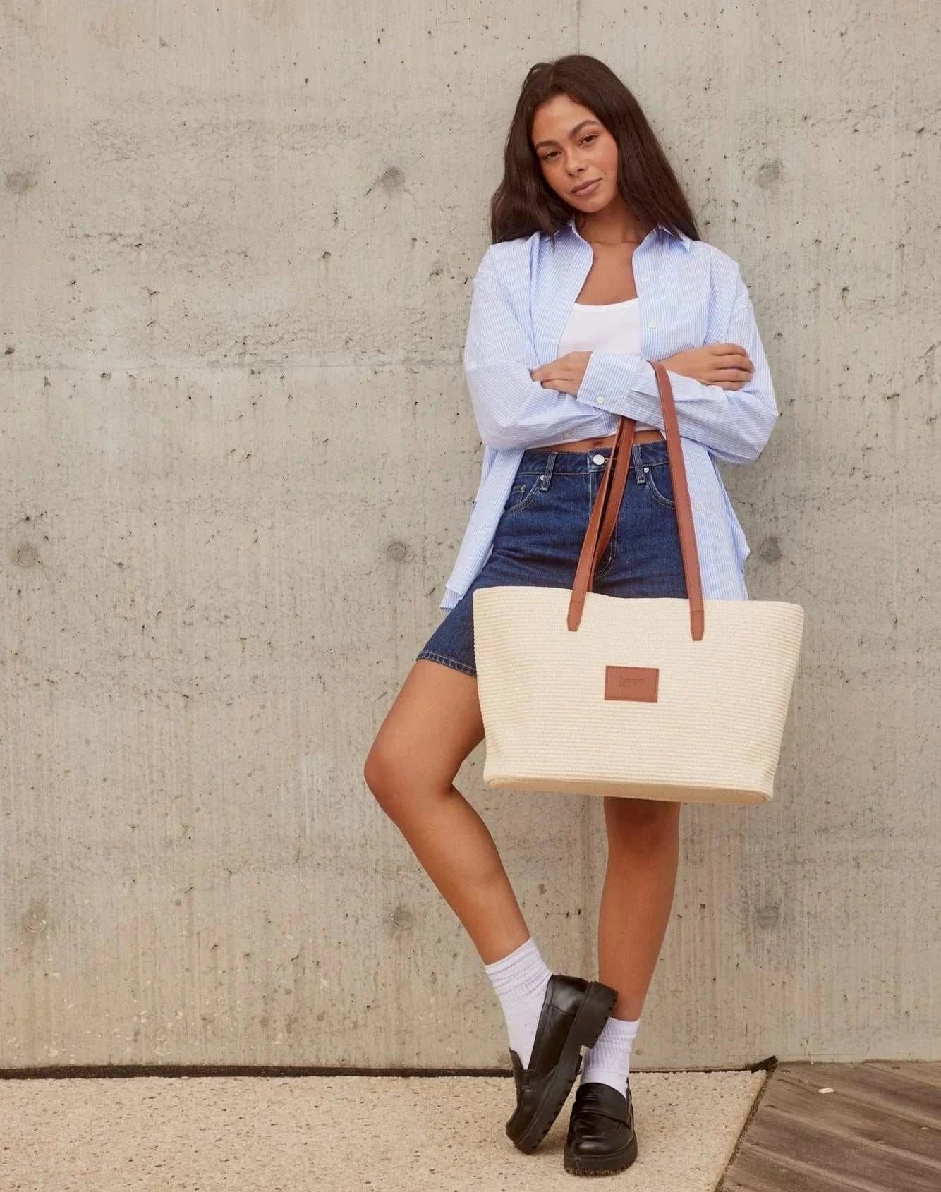 Base Supply Panier tan woven straw basket bag with leather straps and cotton lining held by woman