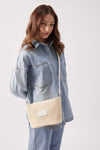 Woman wearing light blue denim outfit carrying a beige Base Supply Panier woven crossbody bag with adjustable strap and zip-top closure
