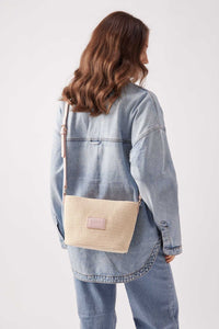 Woman wearing Base Supply Panier Crossbody woven straw bag with adjustable pink strap and cotton lining