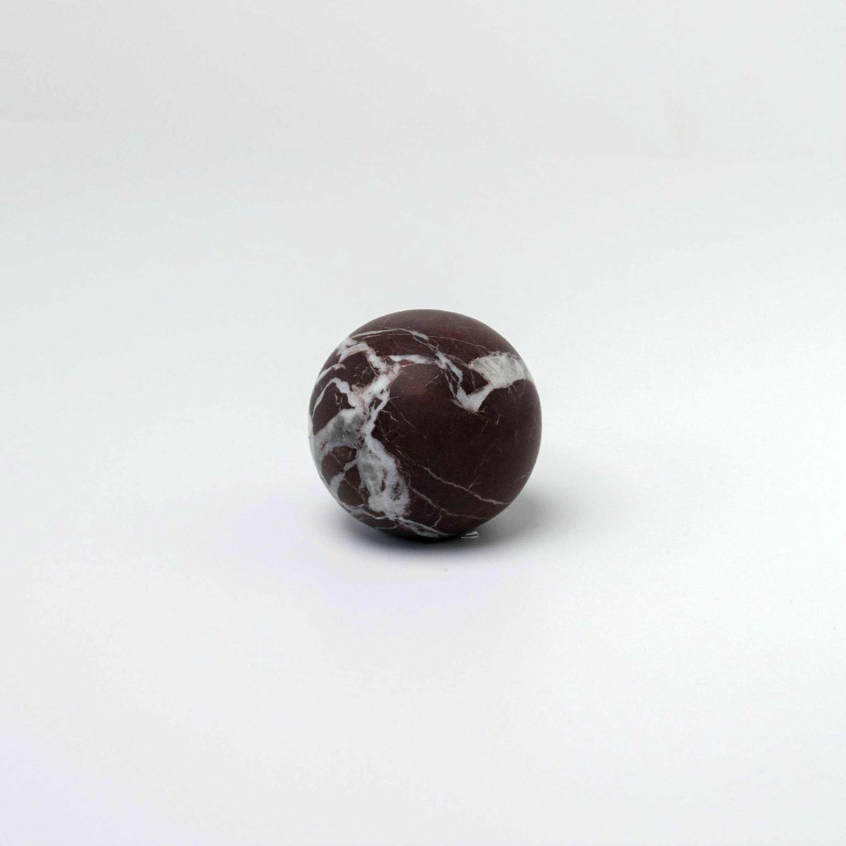 CoTheory Orbit Table Sculpture marble sphere in Rosso Levanto with white veining on a white background