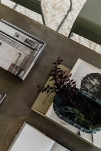 CoTheory Marble Footed Oval Tray in Verdi Alpi with dark green marble and footed design on table with books and plant branch