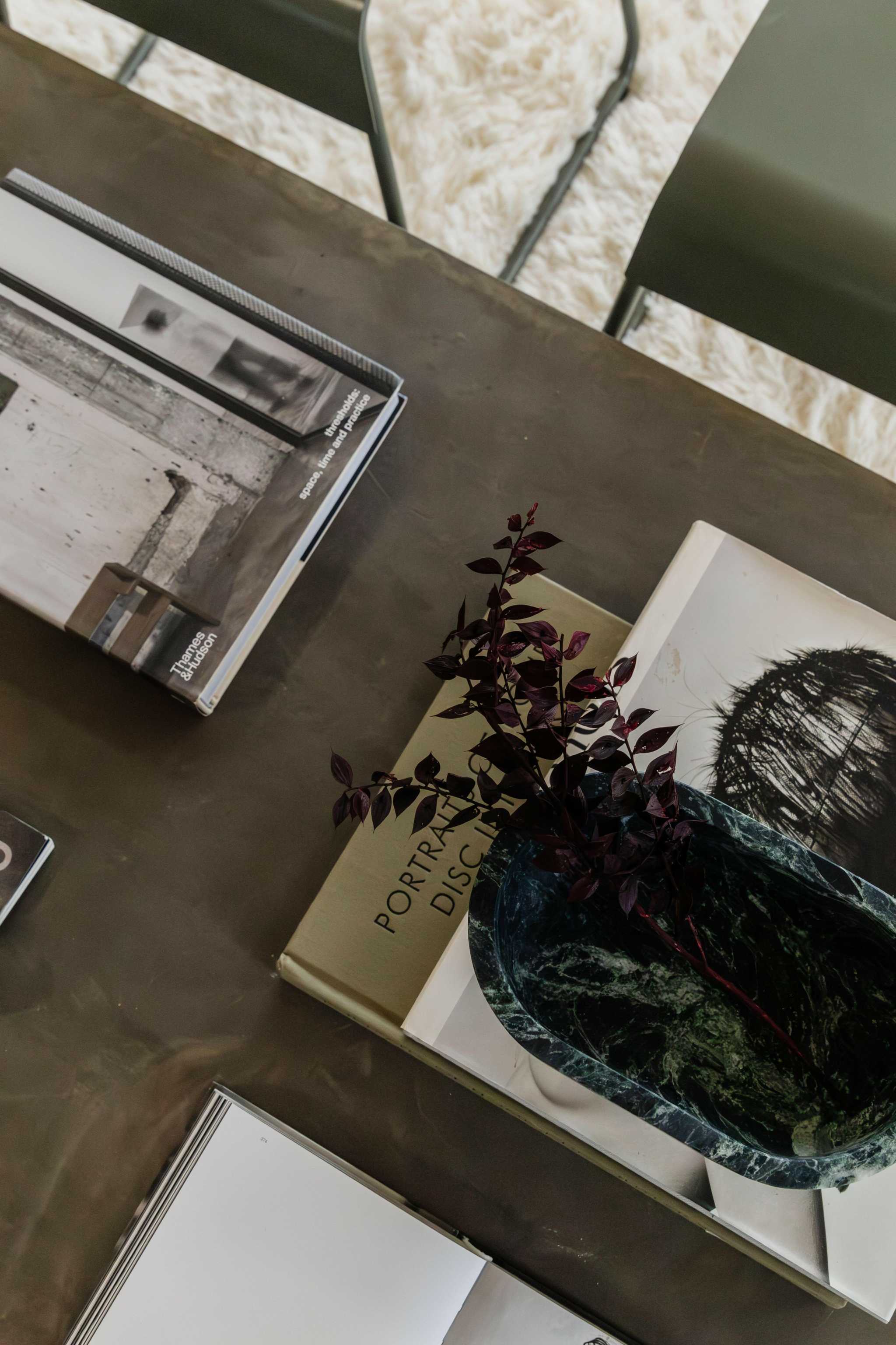 CoTheory Marble Footed Oval Tray in Verdi Alpi with dark green marble and footed design on table with books and plant branch