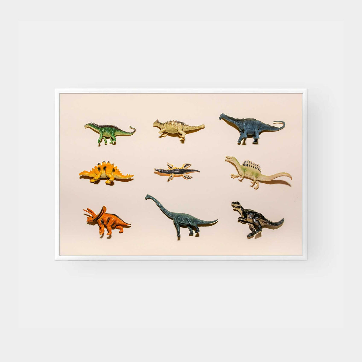 Dinosaur figurine print wall art featuring various colorful dinosaur models on a light background in a white frame