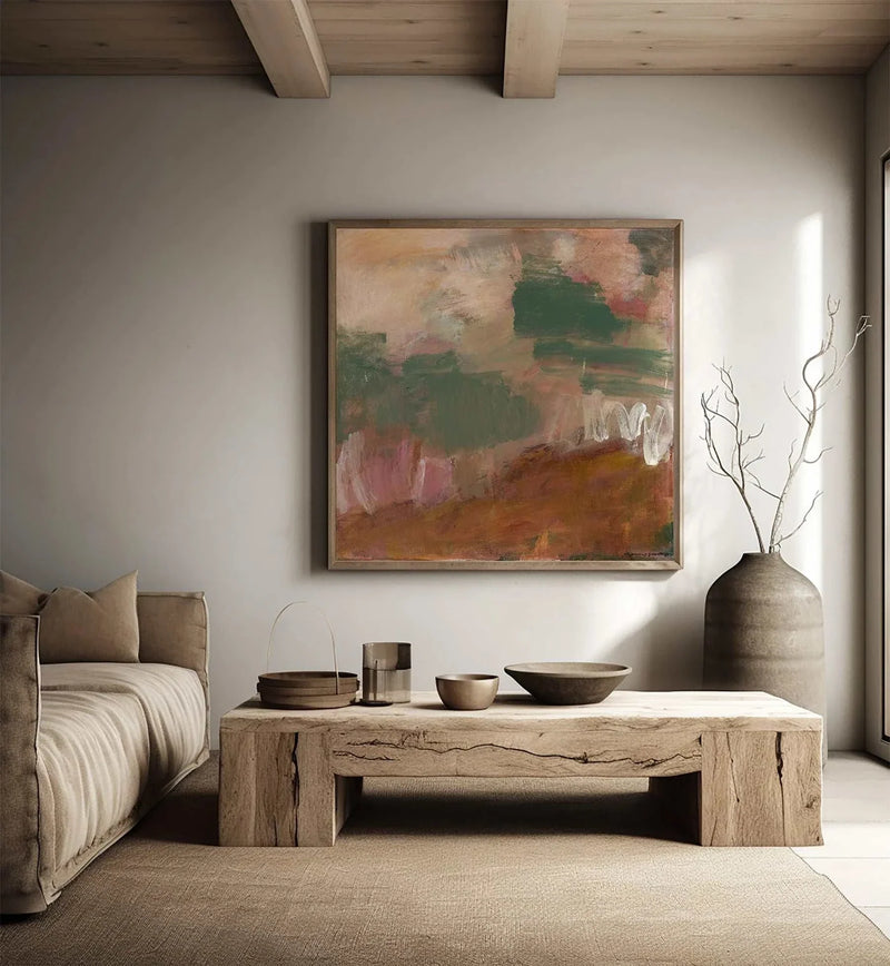 Abstract landscape canvas print by Marcia Priestley with earthy reds, greens, and browns in a floating oak frame above a rustic wooden table in a minimalist living room.