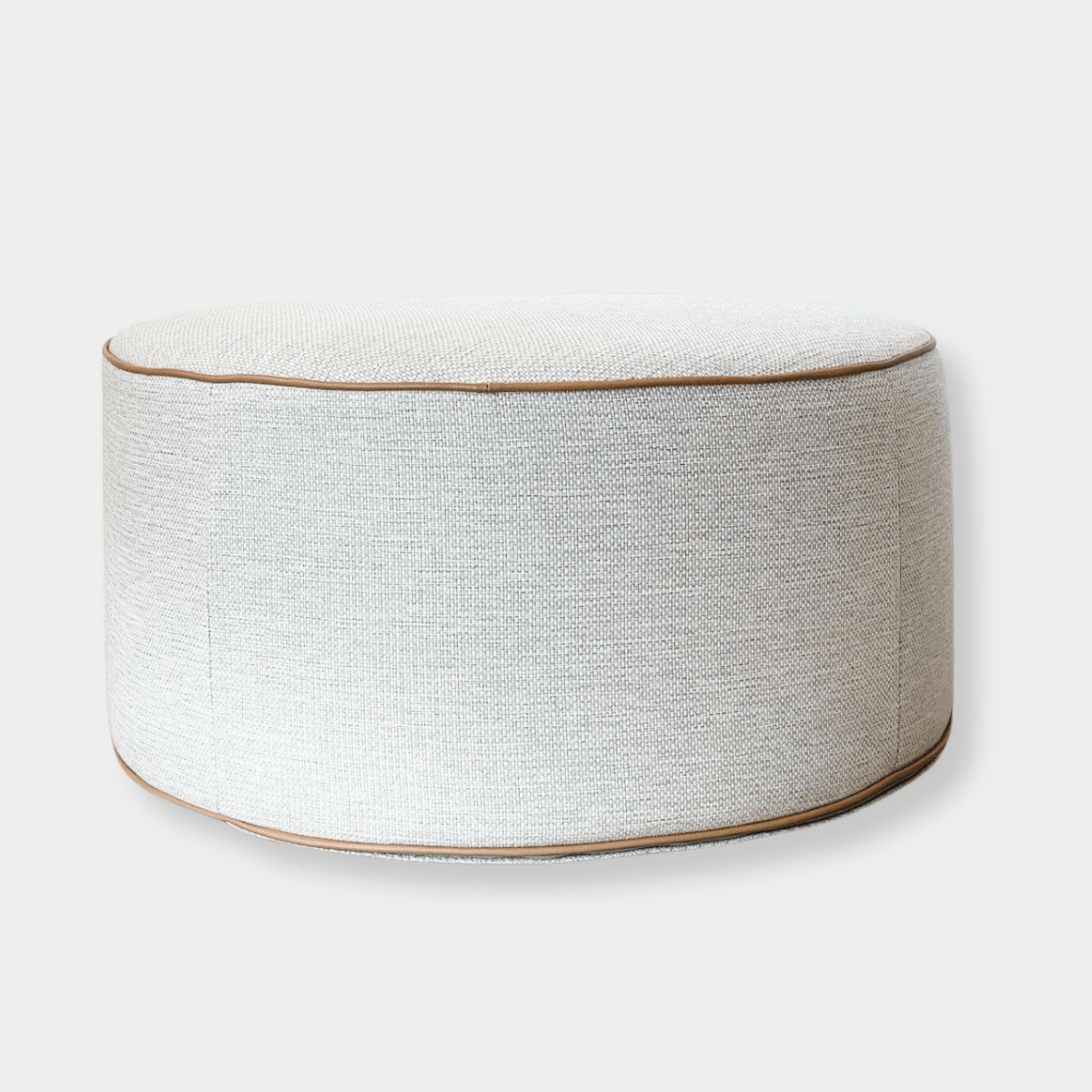 norsu Ottoman in Lindeman Snow fabric with blush leather piping, round soft ottoman with foam coiled filling, available in various sizes