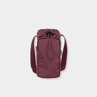 Base Supply Bottle Sling crossbody in burgundy, waterproof, adjustable strap, with front zipped pocket and drawstring top closure.