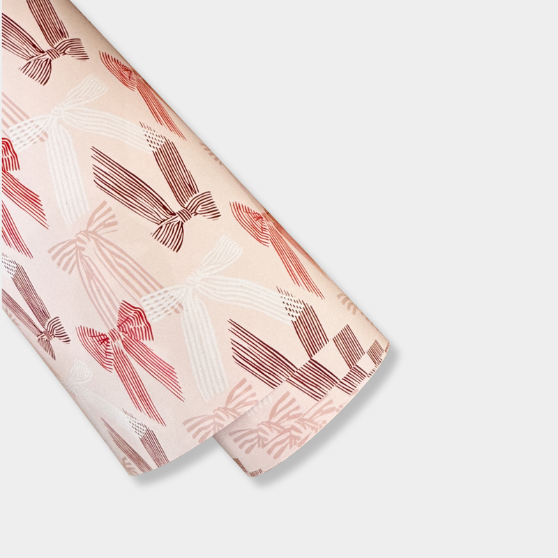 Roll of norsu Studio Christmas Wrapping Paper with pink bow design on pink background, 50 metre jumbo roll