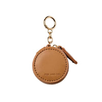 Tan Fox and Leo Eye Catcher bag charm with leather exterior, gold hardware, zipper closure, and circular ring clip, includes microfibre cleaning cloth.