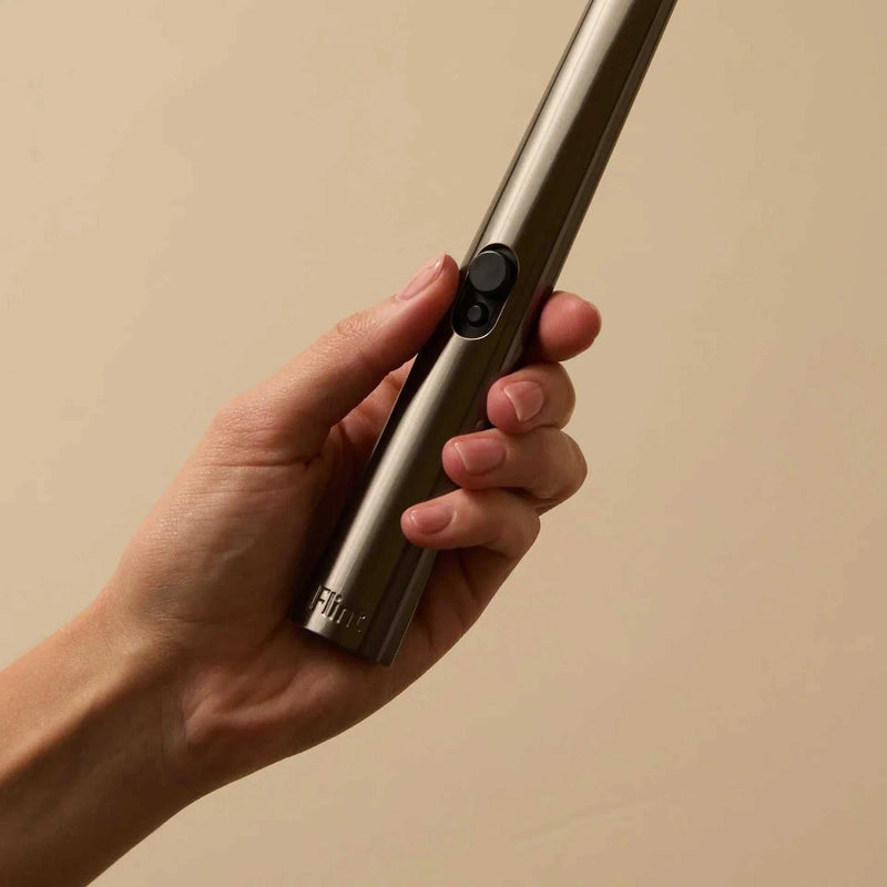 Hand holding a gunmetal rechargeable lighter with a button, designed for eco-friendly ignition of candles, paper, incense, and stovetops