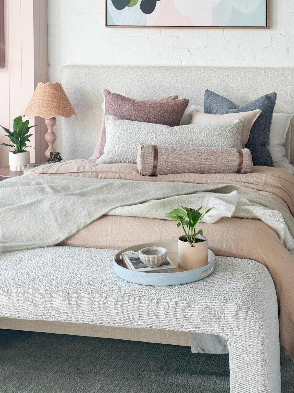 Baya Sorrento Throw in off-white with soft brushed wool texture and feathered fringe on a bed with decorative pillows and neutral decor