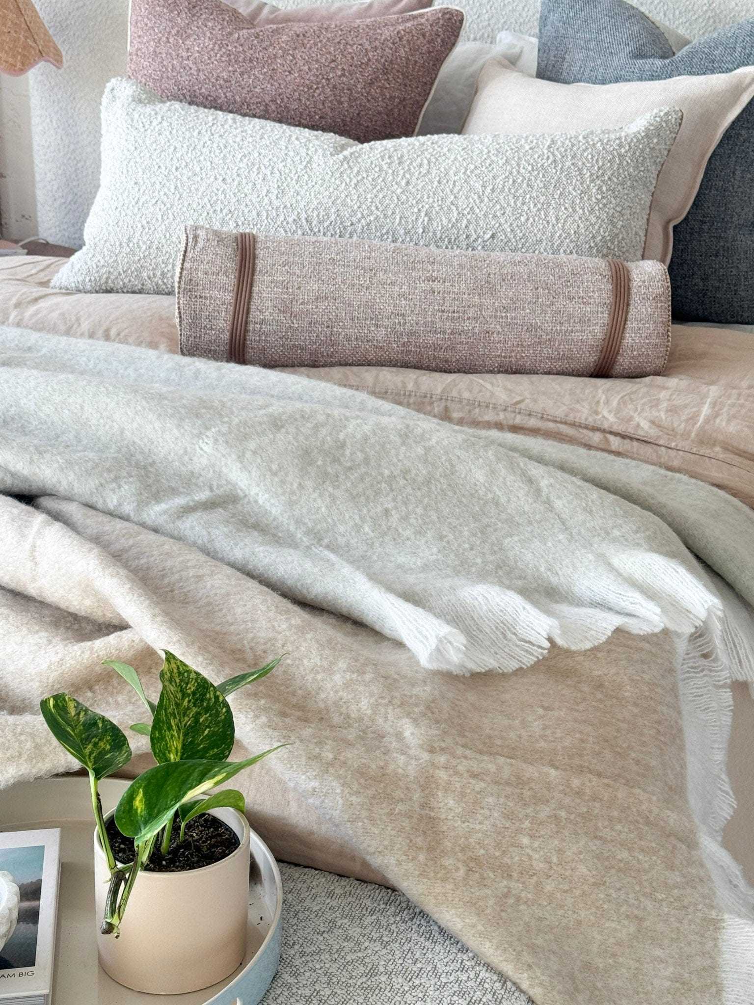 Baya Sorrento Throw off white brushed wool blend with feathered fringe on a neutral bed setting