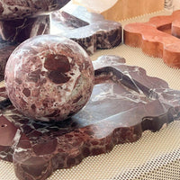 CoTheory Rosso Levanto marble scalloped tray and spherical incense holder in dark red with natural stone patterns