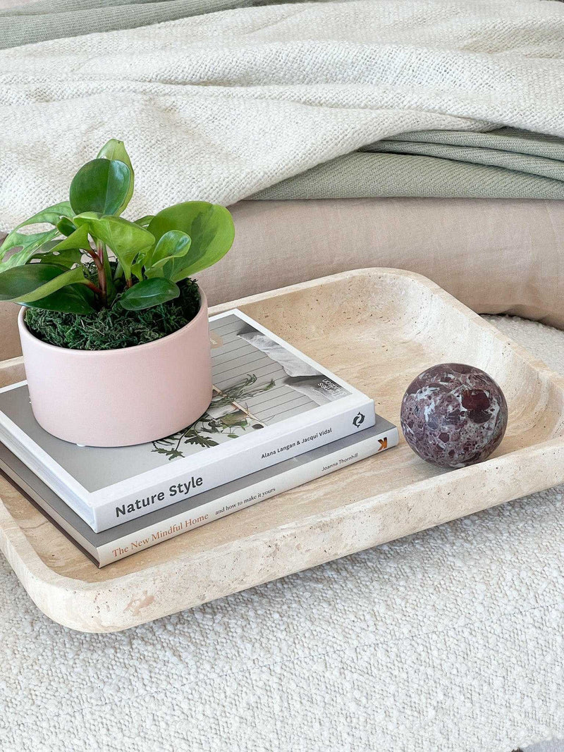 CoTheory Orbit Table Sculpture Rosso Levanto marble sphere on beige tray with books and potted plant
