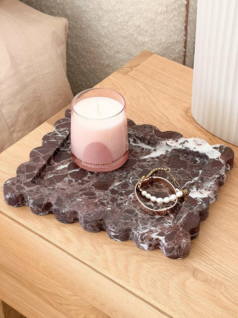 Palazzo Scalloped Marble Bar Tray in Rosso Levanto with candle and jewelry on wooden surface