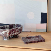 CoTheory Rosso Levanto marble tray and small scalloped incense holder on wooden surface with abstract artwork background