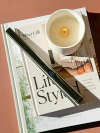 Gunmetal rechargeable lighter placed on books next to a lit candle