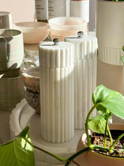Lorne Salt and Pepper Mill made from white marble with sleek vertical grooves, displayed on a kitchen countertop with plants and ceramic accessories.
