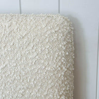 Close-up of ivory Ovis boucle fabric with self-piped trim on norsu Cabin Bedhead King size