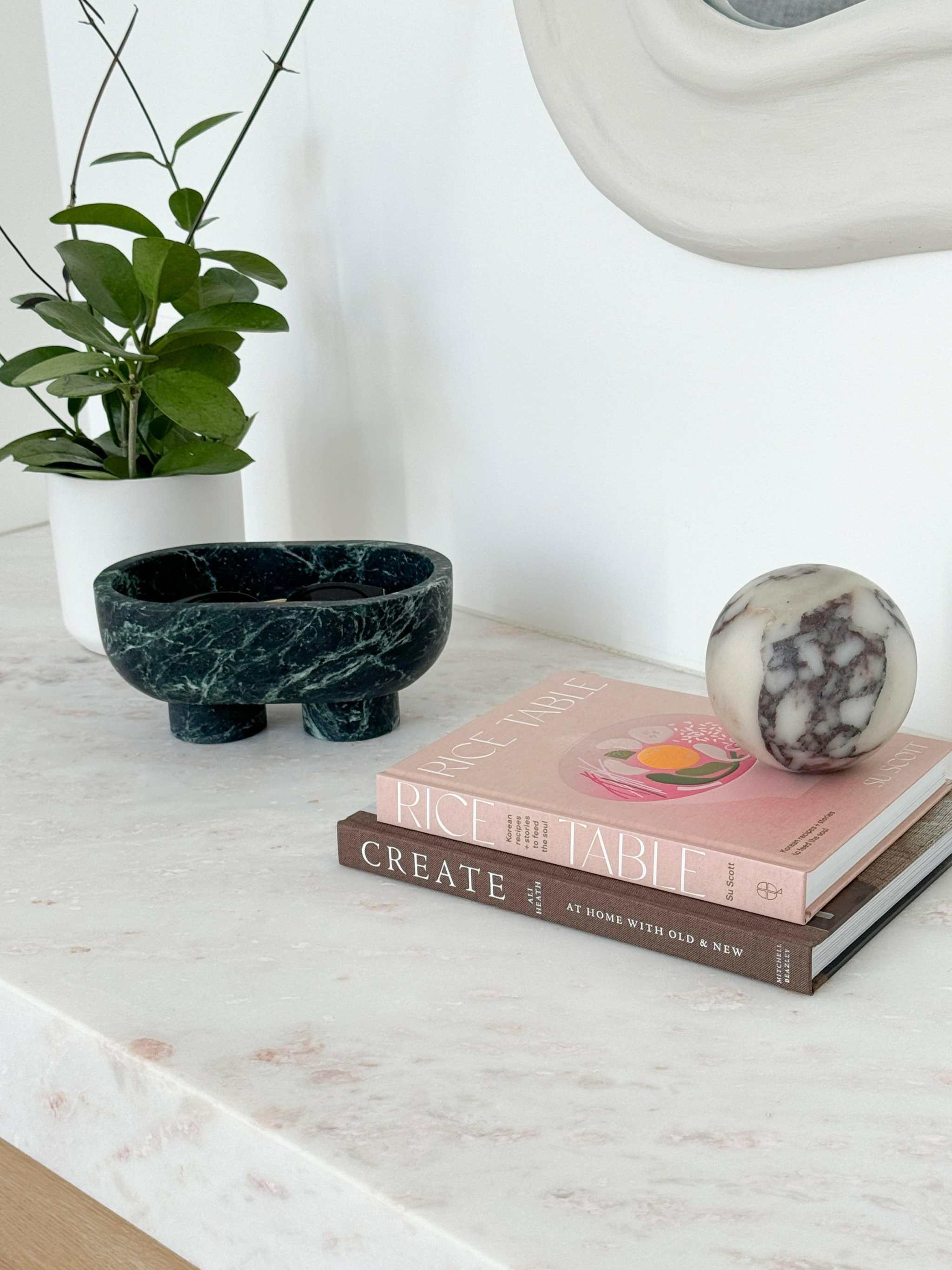 CoTheory marble footed oval tray in verdi alpi on marble countertop with books and plant