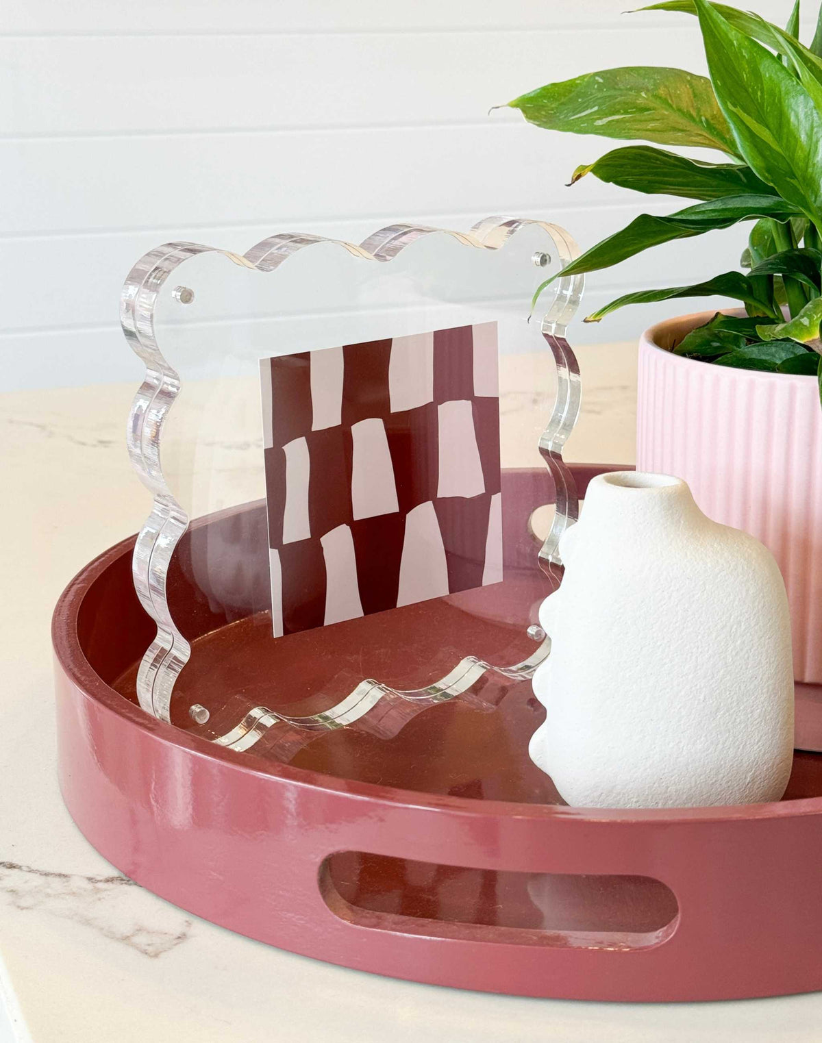 norsu STUDIO Scalloped Magnetic Photo Frame with clear scalloped acrylic design holding a 5x5 photo on a pink tray next to a white vase and green plant