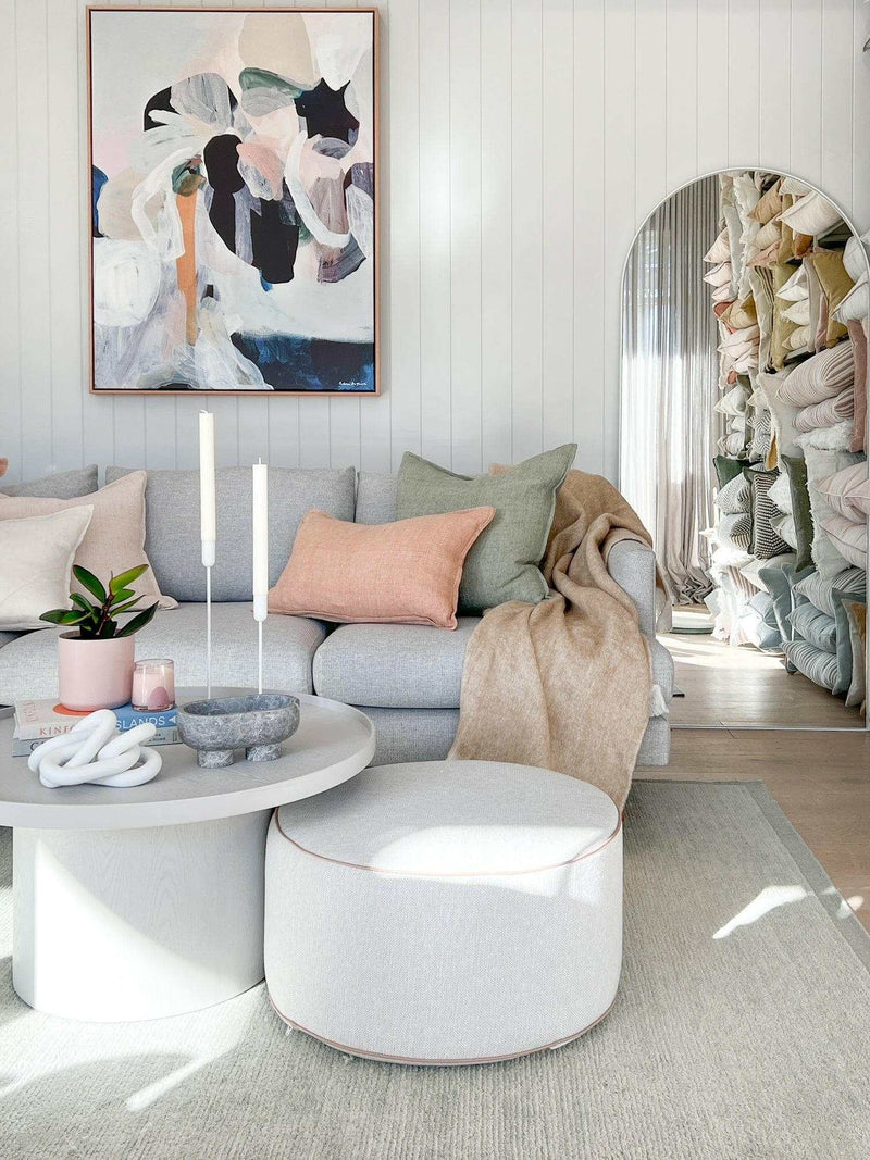 Modern living room featuring Prudence De Marchi's abstract art canvas print "Inconspicuous" with soft pastel tones above a grey sofa with cushions and cozy throws.