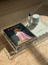 norsu Studio scalloped clear perspex tray holding books and decor on marble surface