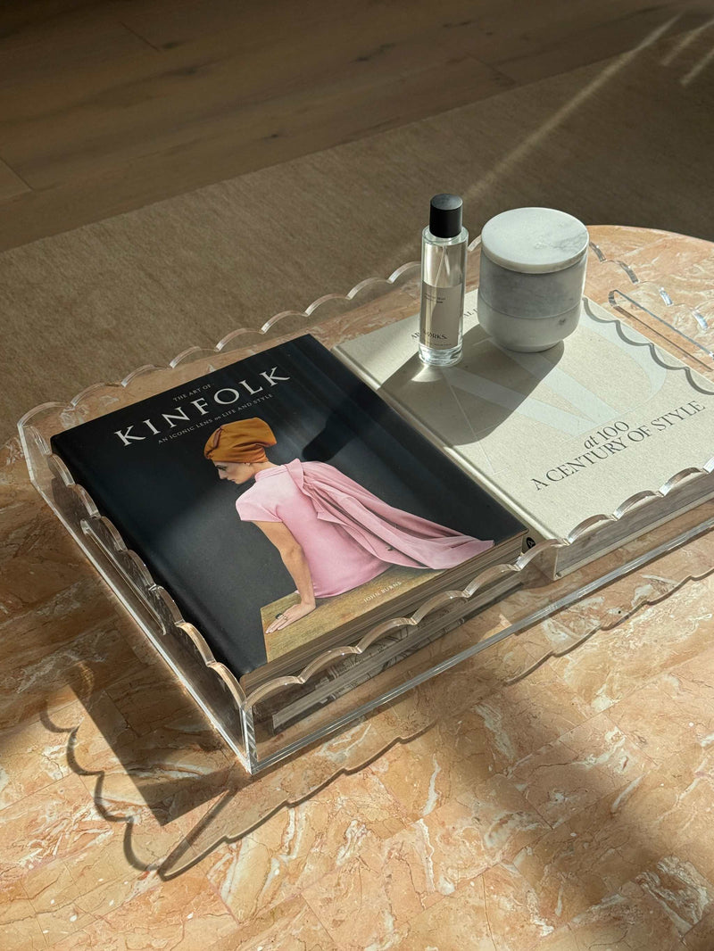 norsu Studio scalloped clear perspex tray holding books and decor on marble surface