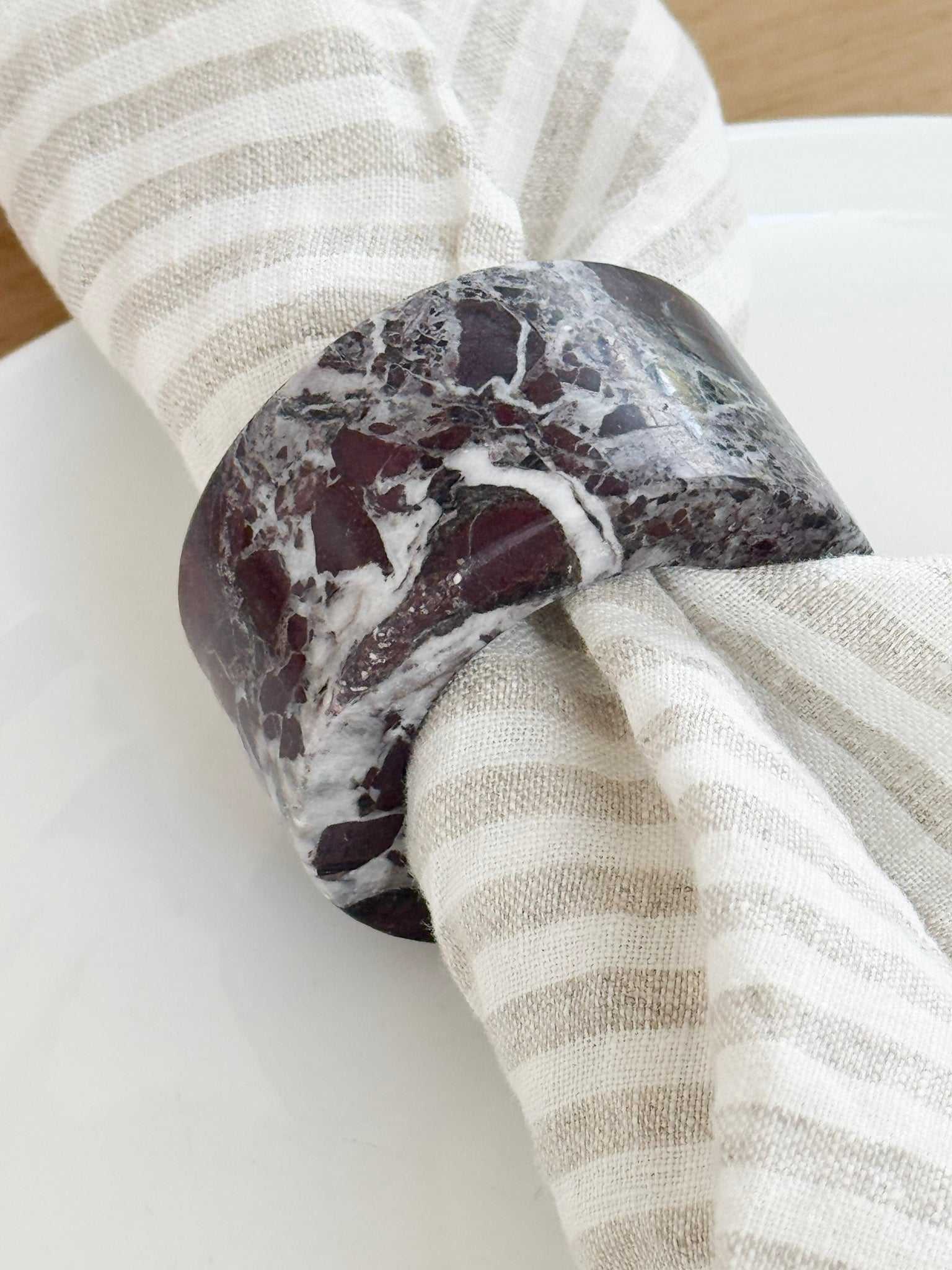 norsu STUDIO Marble Circular Napkin Ring in deep burgundy Rosso Levanto marble with white veining on striped linen napkin