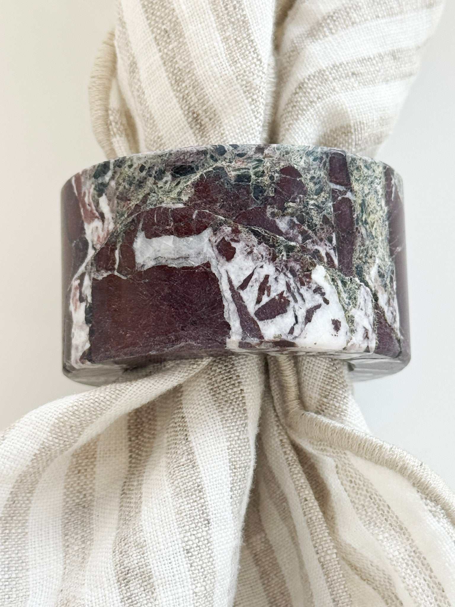 norsu STUDIO Marble Circular Napkin Ring in Rosso Levanto deep burgundy with white veining on striped linen napkin