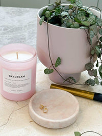 Bondi Scent Candle Daydream in pink jar beside plant in pastel pot and marble tray on stone surface