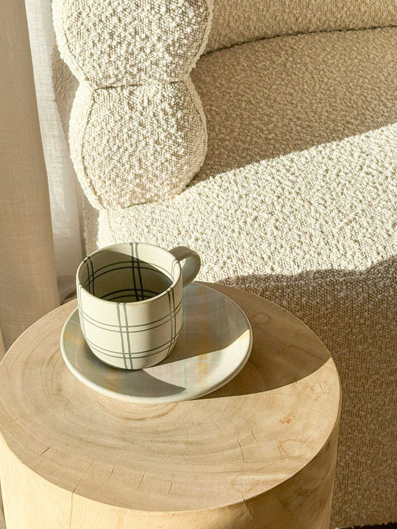 Robert Gordon Hand-Painted Mug with tartan check design on wooden table and textured beige chair background