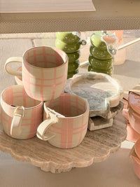 Set of three Robert Gordon hand-painted ceramic mugs with pink tartan pattern on a decorative stone tray