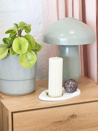 Easton Curve Lamp with elm iron base on wooden table beside plant and decorative candle holder