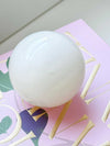 Small white onyx Orbit Table Sculpture sphere resting on a colorful book cover