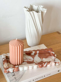 Palazzo scalloped marble bar tray in brown Calacatta with scalloped edges, displayed with candle and vase on wooden surface