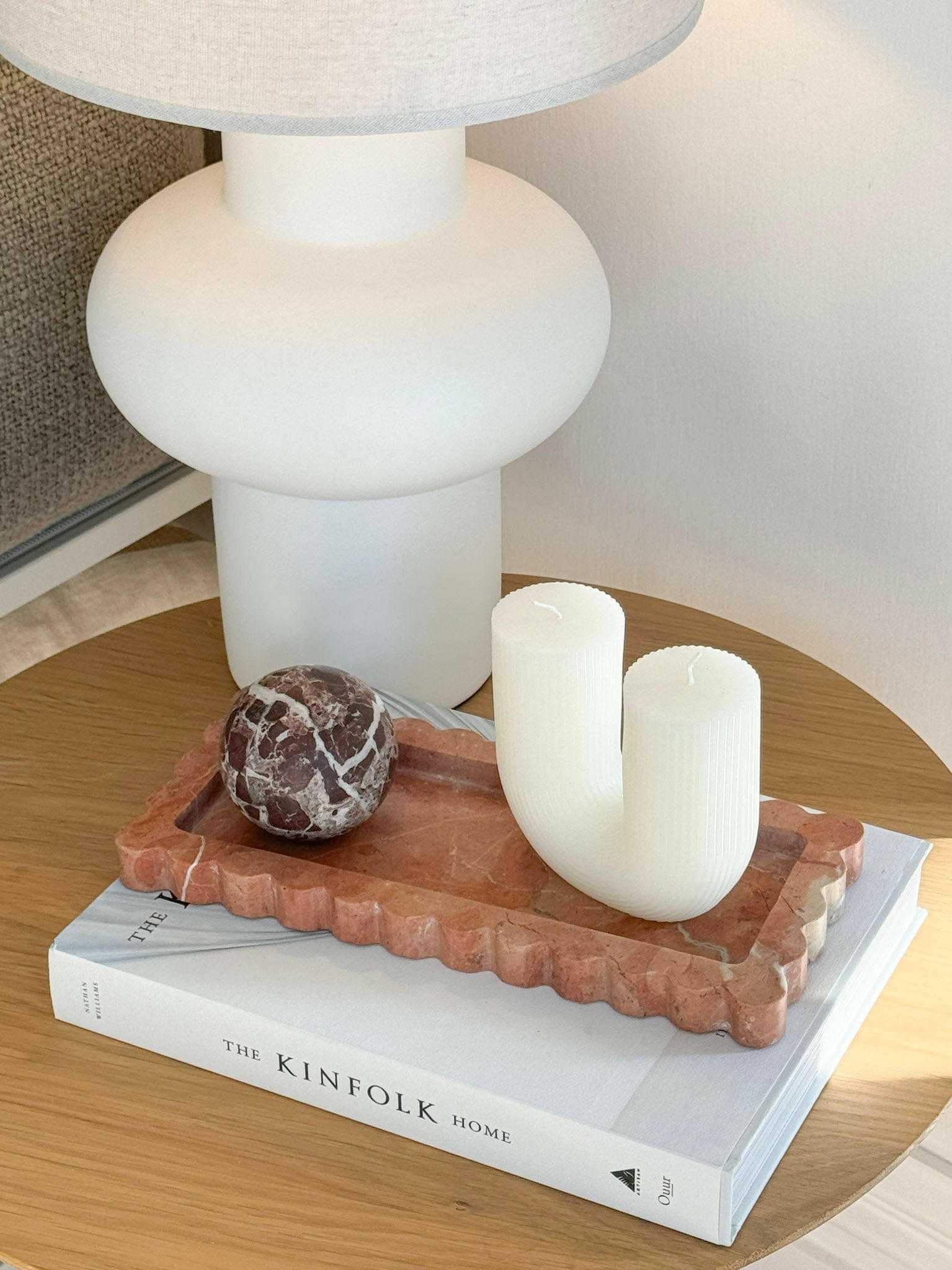 Palazzo Scalloped Marble Tray in Rosso Alicante on wooden table holding decorative candles and marble sphere.